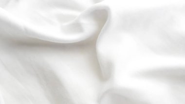 Yumuşak kıvrımlar ve doğal ışık kırışıklıkları gösteren desenli beyaz kumaş.