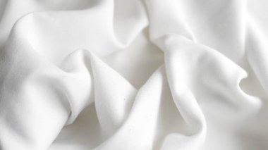 Yumuşak kıvrımları ve pürüzsüz dokuyla kıvrımları gösteren beyaz kumaşın ayrıntılı görünümü