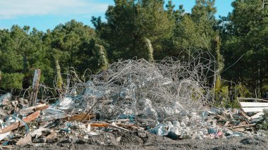 Ormandaki bir alanda karmaşık tel ve plastik atık içeren inşaat enkazı