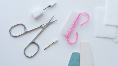 Makas ve dosyaları içeren çeşitli tırnak bakım araçları beyaz bir yüzey üzerinde düzenlendi