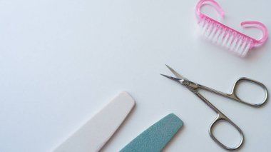 Beyaz bir yüzey üzerinde makas, dosya ve fırça gibi çivi bakım araçları