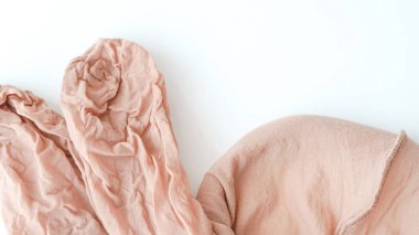 Yumuşak pembe buruşuk kumaş beyaz bir yüzeye örtülmüş. Tekstil tasarım projeleri için ideal.