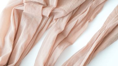 Saf pembe kumaş, beyaz bir yüzey üzerinde akışkan katlar halinde sıralanmış.