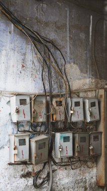 Görünür kablolar ve kablolarla kablo döşeme duvarına birkaç elektrik sayacı bağlanmış.