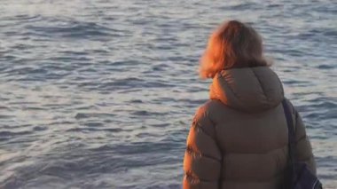 Genç bir kadın sahilde yürüyor.