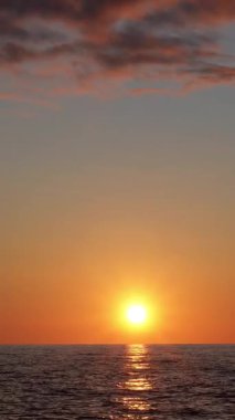 Renkli gökyüzü ve su yansımalarıyla okyanus üzerinde gün batımı manzarası sakin bir atmosfer yaratıyor.