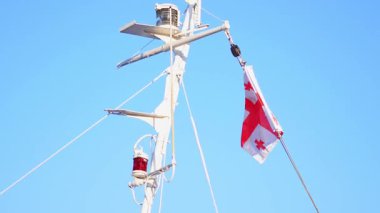 Gürcistan bayrağının gemi direğinde yükselmesi ekipman ve mavi gökyüzü arka planıyla