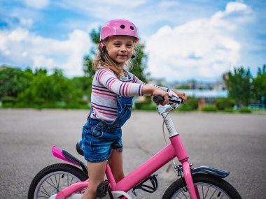 Bisikletli küçük bir kız çerçeveye bakar, geçmişi bulanıktır.,