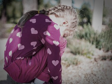 Küçük kız üzgün üzgün oturur izleyiciye