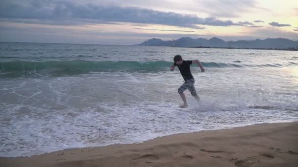 Мужчина бежит по пляжу — стоковое видео