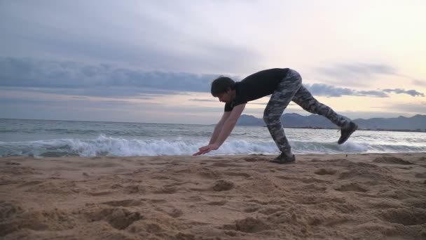 Jovem fazendo truques acrobáticos na praia . — Vídeo de Stock