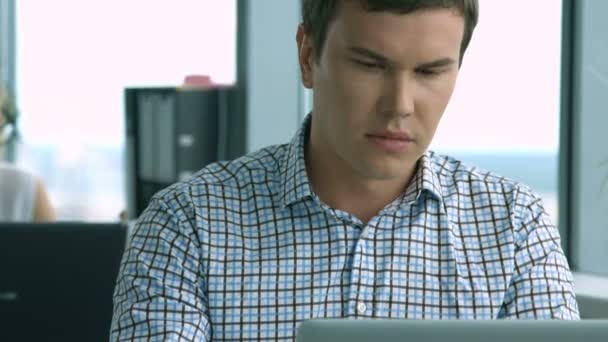 Человек работает на ноутбуке в офисе — стоковое видео