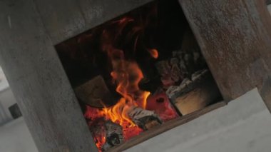 Kesilmiş kütükler şömine kutusunda parlak bir ateş alevi ile yakın çekim görüntüsüyle yanar.