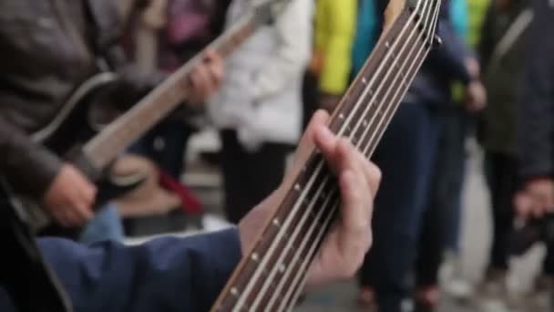 Молодой музыкант играет на бас-гитаре на улице — стоковое видео