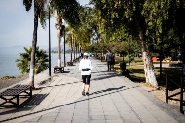 Ajijic, Jalisco, Meksika 'daki Chapala Gölü' nün sahil yolunda (Malecon) sabah koşan kadın.