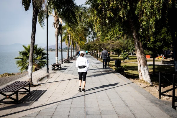 Ajijic, Jalisco, Meksika 'daki Chapala Gölü' nün sahil yolunda (Malecon) sabah koşan kadın.