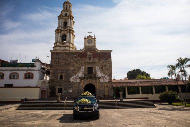 Ajijiç, Jalisco, Meksika - 15 Ocak 2021: Ajijiç 'teki bir koloni kilisesinin önündeki çiçeklerle kaplı siyah cenaze arabası