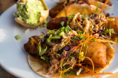 Battered fish tacos topped with slaw and salsa, served with guacamole at a restaurant on the beach of Bucerias, Mexico clipart