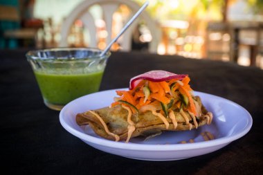 Kızarmış, sert kabuklu taco soslu, lahana salatası ve turplu beyaz tabakta. Bu yemek Meksika 'daki Riviera Nayarit' te bir plaj restoranında servis ediliyor..