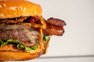 Peynirli, kızarmış, soğanlı, marullu, pastırmalı, susamlı ekmeğin üstünde barbekü soslu, beyaz bir arkaplan ekmeği..