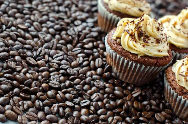 Muffins met karamel crème op koffiebonen achtergrond — Stockfoto