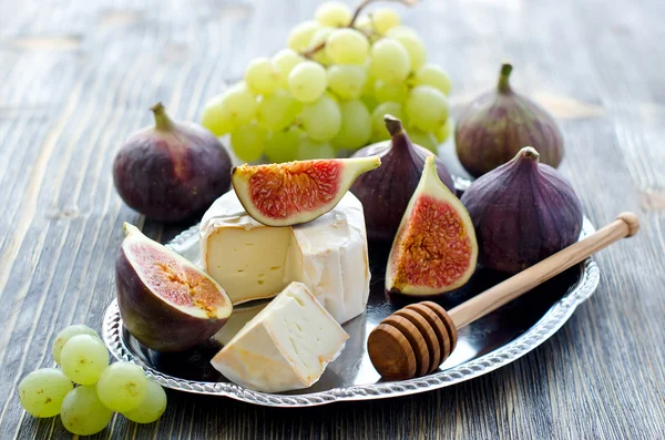 Delicious snack cheese, figs and grapes. Wooden background — Stock Photo, Image