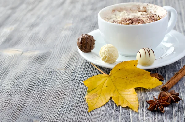 Pralinen, eine Tasse Cappuccino und Herbstblätter — Stockfoto