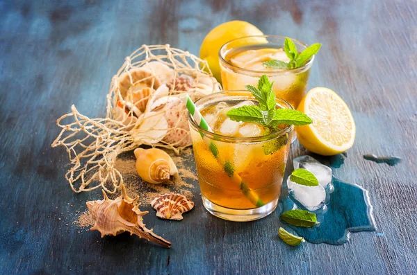 Fresh cold iced tea with mint, ice,  lemons and sea shells, refr