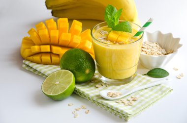 Yellow smoothie in glasses with mango and tropical fruits