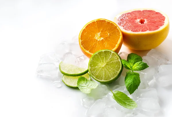 Citrus fruits with mint and cubes of ice on white copy space bac — Stock Photo, Image