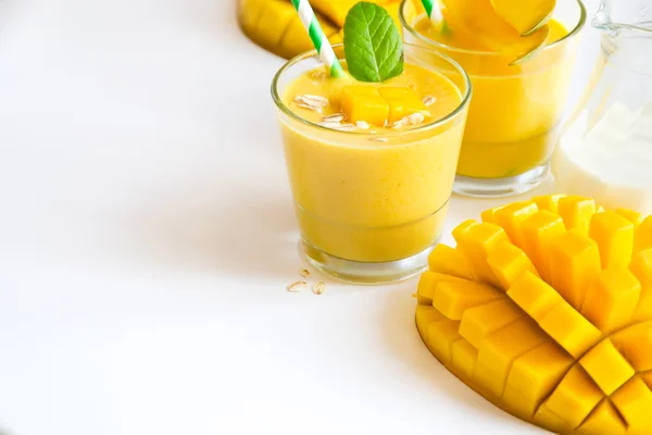 Yellow smoothie in glasses with mango white copy space backgroun