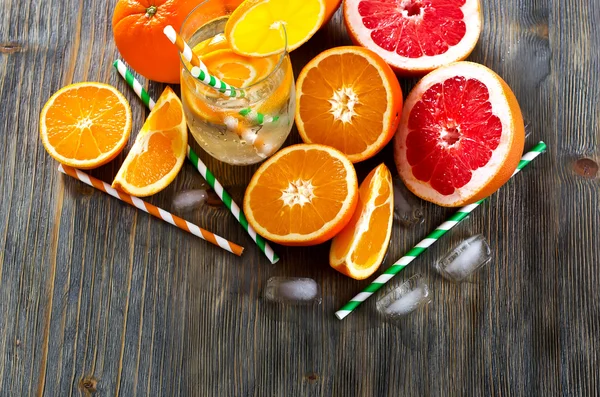 Laranja fresca e toranjas com copo de água e palhas — Fotografia de Stock