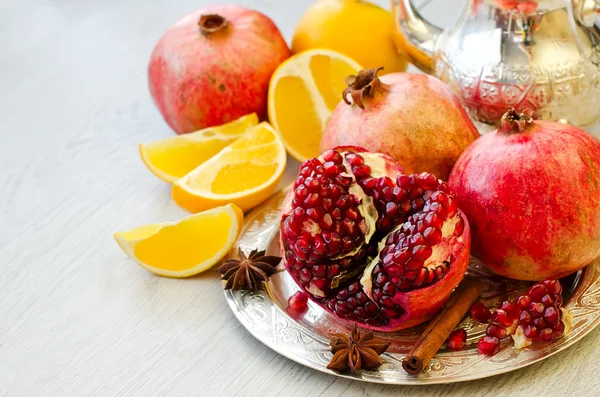 Frutas maduras granada y naranja en un plato de plata —  Fotos de Stock