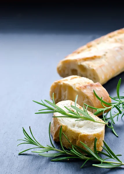 French bread baguette with rosemary on black background — Stock Photo, Image