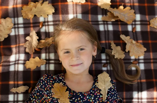 幸せな笑顔の女の子の子供のポートレートを閉じる上のビューでは黄色のカエデの葉で遊んで — ストック写真