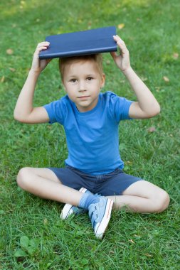 Tatlı küçük çocuk. Parkta bir kitap oku.