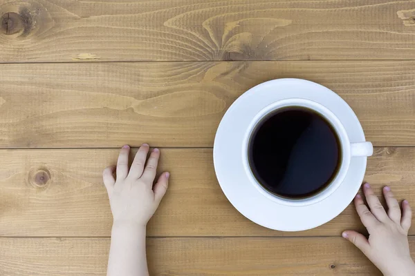 Woman\'s hands in sweater holding cup of coffee on the black wooden table.