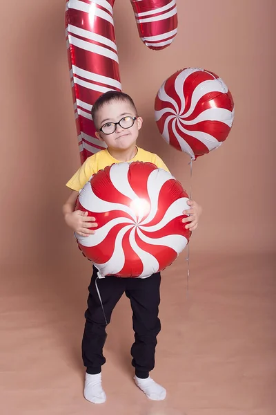 Happy boy met bril uitgeschakeld met Down syndroom glimlacht naar de camera, met ballonnen. — Stockfoto