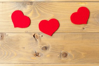 Tahta arka planda üç kalp var. Gri yaşlı ağaçta kırmızı kalpler