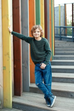 Genç bir çocuk arkadaşlarıyla aktif bir yürüyüşten sonra parkta dinleniyor, birlikte basketbol oynadılar. Genç açık havada oynadıktan sonra mutlu bir şekilde gülümser..