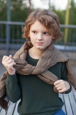 Genç bir çocuk arkadaşlarıyla aktif bir yürüyüşten sonra parkta dinleniyor, birlikte basketbol oynadılar. Genç açık havada oynadıktan sonra mutlu bir şekilde gülümser..