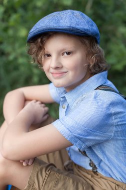 Yaz parkında palmiye ağaçlarıyla poz veren genç bir çocuk. Sevimli, gözlüklü, gülümseyen, 13 yaşında, kameraya bakan genç bir çocuk. Çocuğun açık hava portresi..