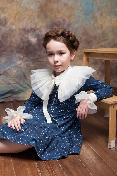 Portrait of a little girl posing in a blue dress with a ruffled collar of the late Renaissance.