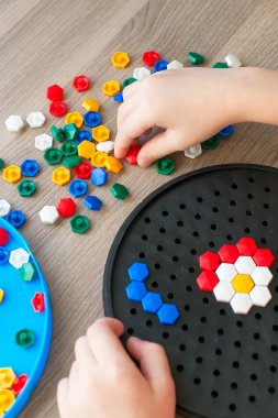 Çocuk renkli bir mozaikten bir çiçek heykeli topluyor. Erken eğitim, gelişme.