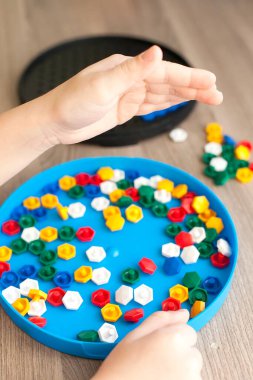 Beyaz tişörtlü küçük sarışın kız evde ya da anaokulunda plastik renkli mozaikle oynuyor. Erken eğitim kavramı.
