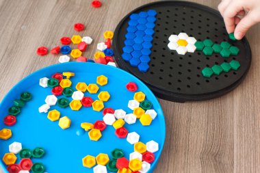 Bir çocuk, çocuk odasındaki halının üzerinde plastik bir mozaikle oynuyor. Erken gelişme.