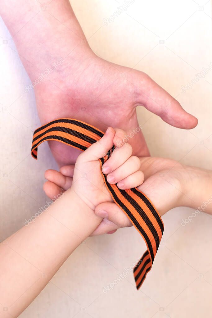 St. George ribbon in three children's hands, Defender of the Fatherland Day, Greeting card concept. Victory Day. 9th May. symbol of victory.