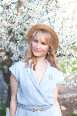 Baharda açan bahçede uzun saçlı genç bir kadın.