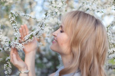 Genç esmer kadın dallarda çiçek açan beyaz elma çiçekleriyle poz veriyor..