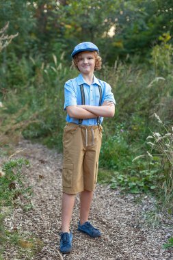 Parkta bacak bacak üstüne atmış, güneşli bir günde dinlenen ve kameraya gülümseyen çekici bir gencin düşük perspektifli portre görüntüsü. Açık hava yaşam tarzı.